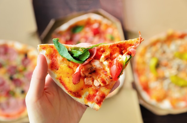 Feminino mão tomando fatia de pizza fresca da caixa de entrega.