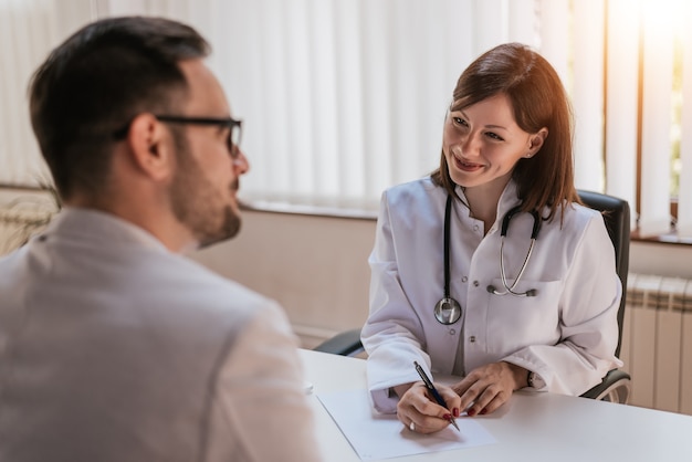 Feminino médico falando com o paciente no escritório