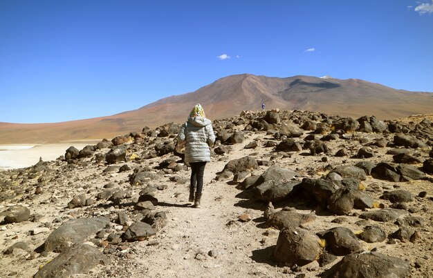 Foto feminino viajante andando na encosta da margem do lago laguna verde, potosi, bolívia