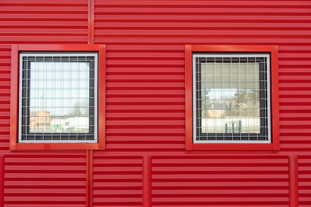Fenster in rotem Wandfenster mit Gitterdetails der geschützten Mauer des Gebäudes