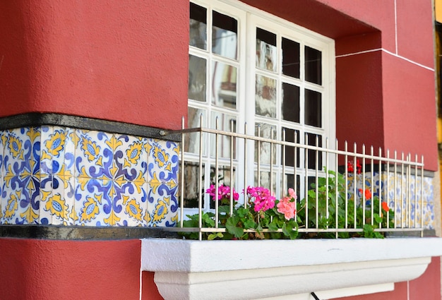 Fenster mit einer Geranie auf der Fensterbank und Azulejo-Fliesen