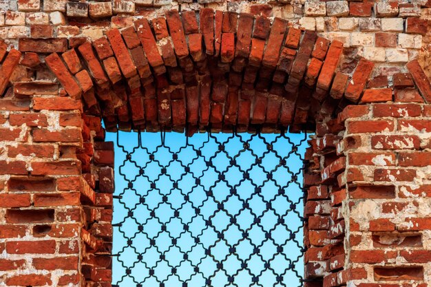 Fenster mit Eisengitter in einer Wand des alten Gebäudes aus rotem Backstein