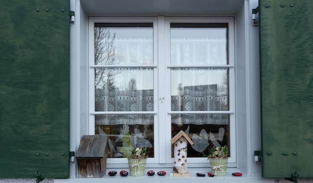 Fenster mit Vorhängen und Bienenhotels auf dem Fensterrand