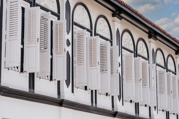 Fenster mit weißen Fensterläden aus Holz am Wandgebäude Singapur