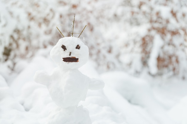 Feo muñeco de nieve en el parque cubierto de nieve