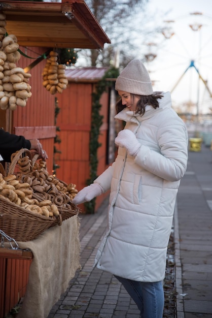 feria de compras navideñas niña vestida con una chaqueta blanca y un sombrero blanco la niña sonríe la niña hace compras la niña se regocija de las emociones