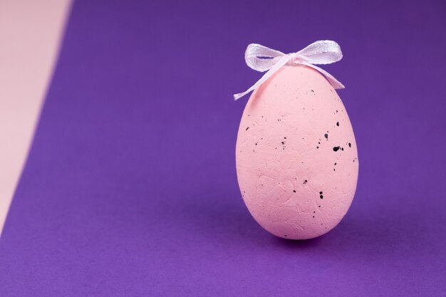 Feriado da Páscoa. Ovo-de-rosa com decoração em um fundo roxo.