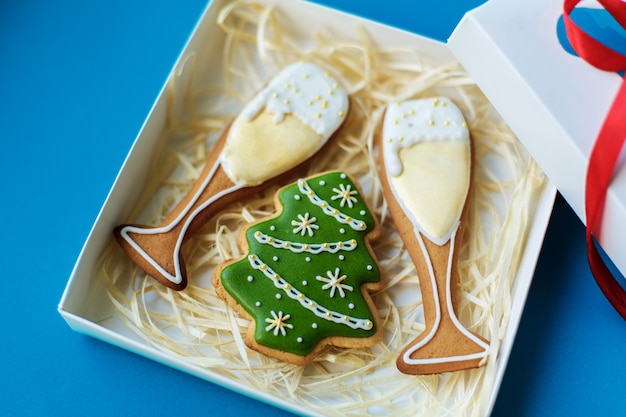 Feriado de ano novo de Natal, copos de campagne e pão de gengibre de árvore de Natal embalado em caixa no feriado de fundo azul