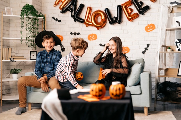 feriado de halloween e conceito de infância crianças sorridentes com abóboras em casa