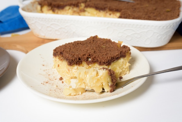 Feriado de Hanukkah, tradicional torta Kugel doce com macarrão e creme, migalhas de cacau amanteigadas por cima. sobre um fundo claro em uma assadeira. fatias de torta em um prato.