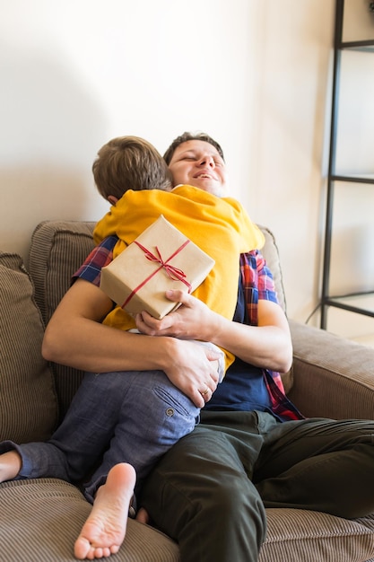 Feriado do dia dos pais. Menino bonito está dando uma caixa de presente artesanal para seu pai. Família feliz, tempo juntos, fique em casa.