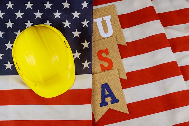 Feriado federal feliz Día del trabajo construcción casco amarillo herramientas sobre bandera americana.