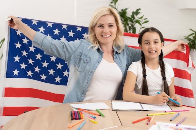 Feriado patriótico. Família feliz, mãe e sua filha filha com bandeira americana em casa. EUA comemoram 4 de julho.