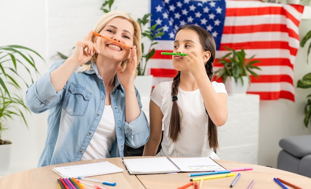 Feriado patriótico. Família feliz, mãe e sua filha filha com bandeira americana em casa. EUA comemoram 4 de julho.