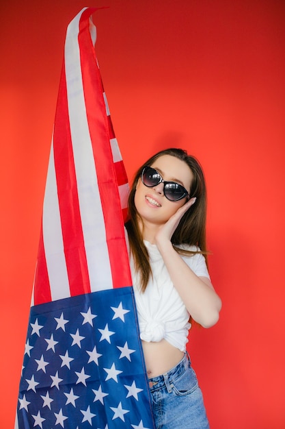 Feriado patriótico Jovem feliz com bandeira americana em fundo vermelho EUA comemora 4 de julho