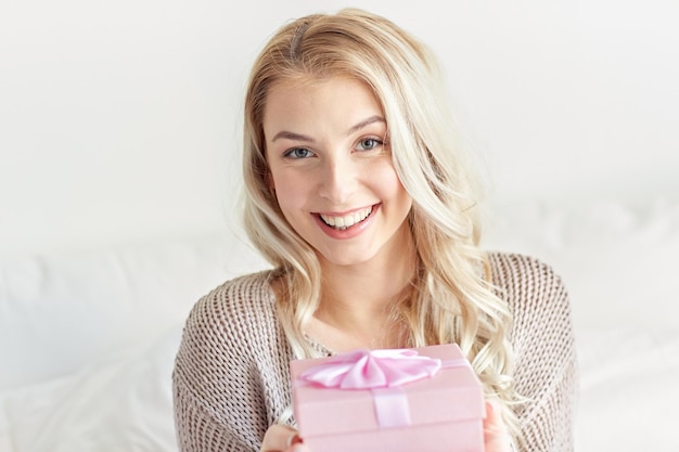 feriados, aniversário, manhã e conceito de pessoas - caixa de presente de mulher jovem feliz ou presente em casa