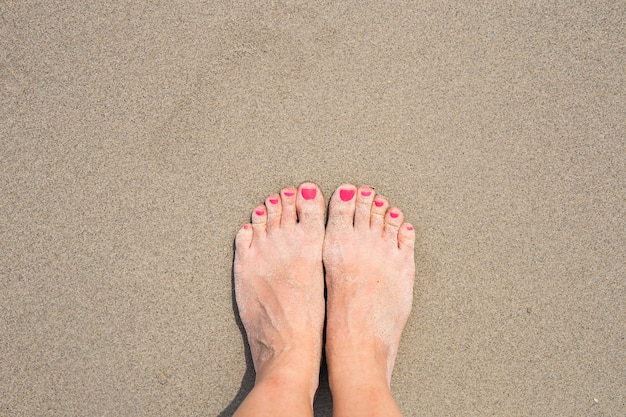 Feriados de férias. Close up dos pés da mulher da menina que relaxa na praia no dia de verão ensolarado.