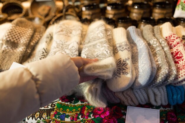 feriados e roupas de inverno conceito - close de mulher comprando luvas de lã no mercado de Natal