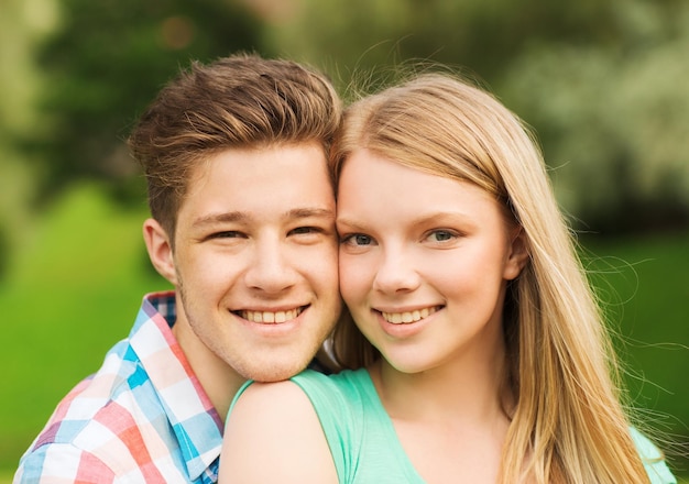 feriados, férias, conceito de amor e amizade - casal sorridente abraçando no parque