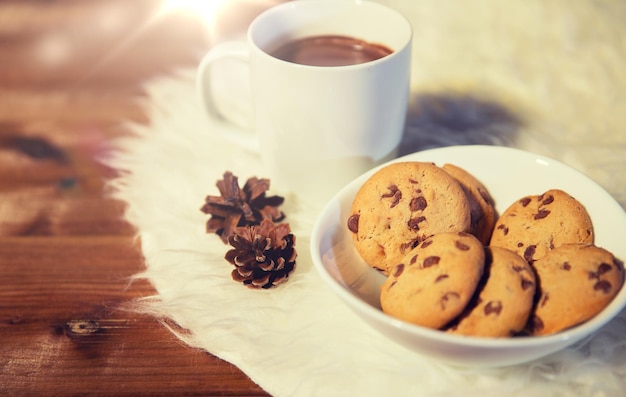 feriados, natal, inverno, conceito de alimentos e bebidas - close-up de xícaras com chocolate quente ou bebidas de cacau e biscoitos de aveia no tapete de pele branca