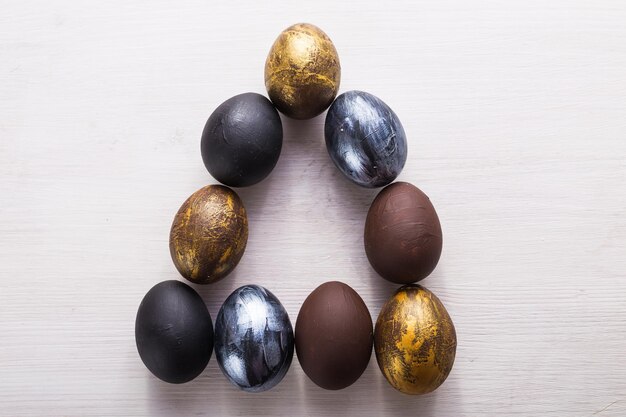 Feriados, tradições e o conceito de páscoa - ovos de páscoa elegantes escuros sobre fundo branco de madeira.