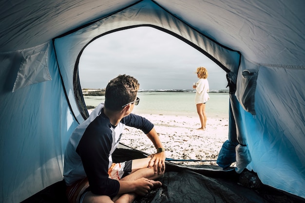 Férias alternativas desfrutando de liberdade total com barraca acampada na praia de areia branca e oceano azul e céu casal de pessoas brancas curtindo o mundo nas férias de verão wanderlust e aproveite