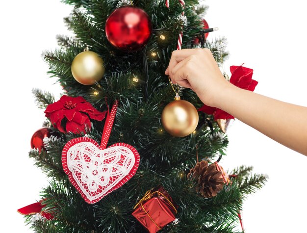 Férias de inverno, celebração e conceito de pessoas - close-up de uma mulher decorando a árvore de Natal com uma bola