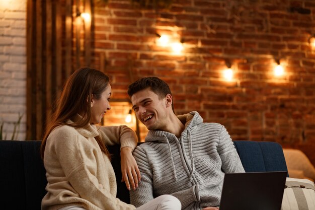 Férias de inverno, celebrações do Natal, conceito de ano novo. Retrato de um lindo casal sorridente, assistindo filme de Natal em casa. Lindo casal jovem em casa desfrutando de passar algum tempo juntos.