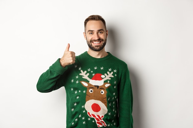 Férias de inverno e natal. Homem barbudo feliz mostrando o polegar em aprovação, tipo algo, elogie o bom trabalho, de pé sobre um fundo branco