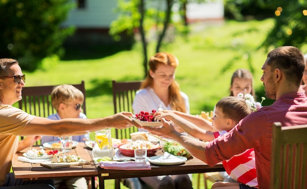 férias de lazer e pessoas conceito família feliz tendo jantar festivo ou festa de jardim de verão