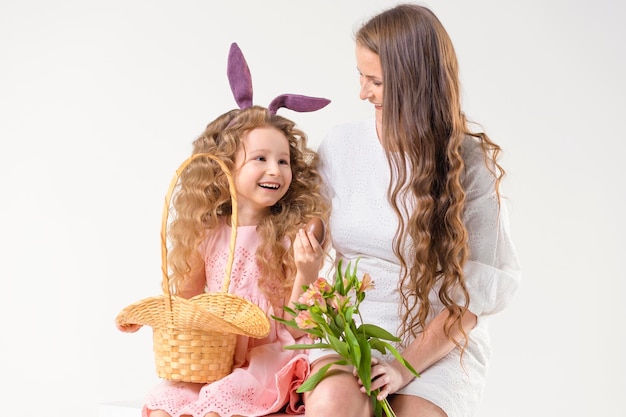 Férias de páscoa crianças família mulher e menina coelho lebre orelhas de coelho brincando com ovos de chocolate na cesta