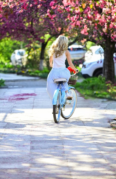 Foto férias de primavera mulher passeio bicicleta vintage garota romântica sob sakura flor linda primavera estação natureza cerejeira flores desabrochando rosa florescendo sakura relaxe no parque moda e beleza