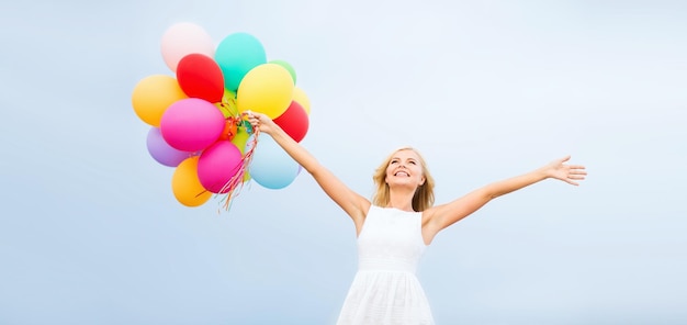 Férias de verão, celebração e conceito de estilo de vida - linda mulher com balões coloridos do lado de fora