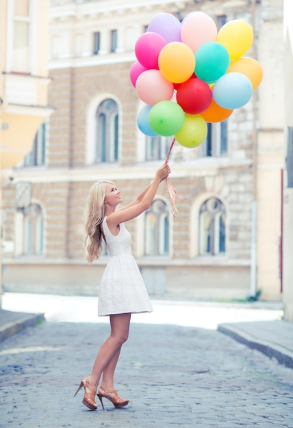 férias de verão, celebração e conceito de estilo de vida - linda mulher com balões coloridos na cidade