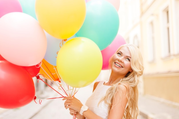 férias de verão, celebração e conceito de estilo de vida - linda mulher com balões coloridos na cidade