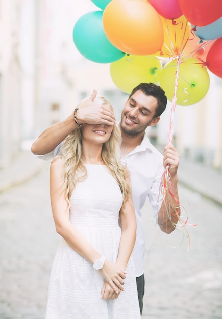 férias de verão, celebração e conceito de namoro - casal com balões coloridos na cidade