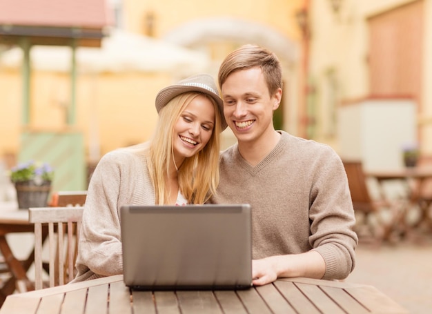 férias de verão, cidade, namoro e conceito de tecnologia - casal com laptop no café