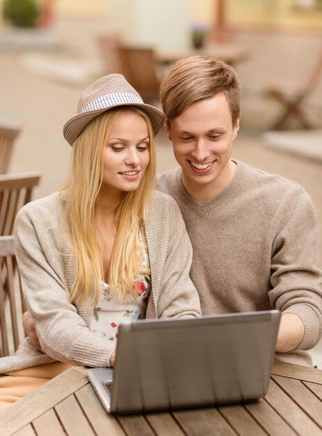 férias de verão, cidade, namoro e conceito de tecnologia - casal com laptop no café