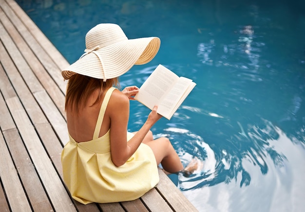 Férias de verão com um grande livro jovem relaxante na piscina com um livro