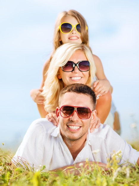 férias de verão, crianças e conceito de pessoas - família feliz com céu azul e grama verde