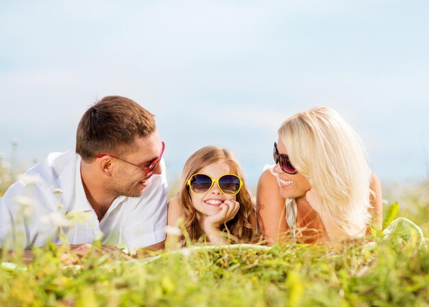 férias de verão, crianças e conceito de pessoas - família feliz com céu azul e grama verde