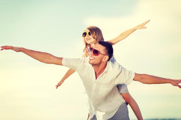 Férias de verão, crianças e conceito de pessoas - feliz pai e filho em óculos de sol sobre o céu azul