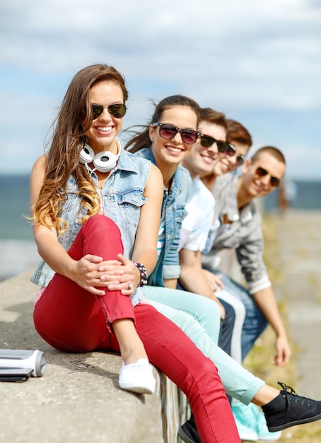 férias de verão e conceito adolescente - adolescente sorridente em óculos de sol saindo com amigos ao ar livre