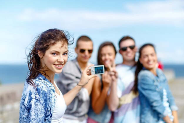 Férias de verão e conceito adolescente - grupo de adolescentes felizes tirando foto lá fora