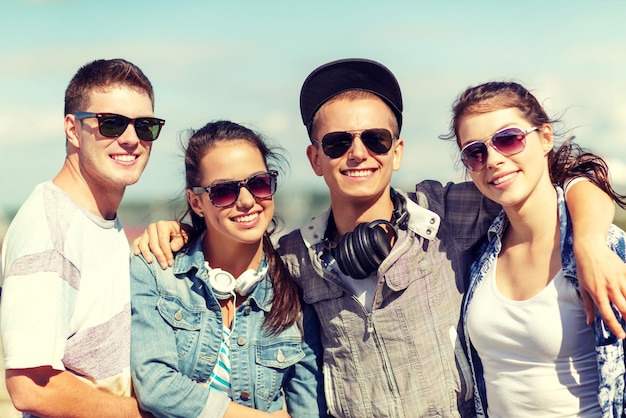 férias de verão e conceito adolescente - grupo de adolescentes sorridentes em óculos de sol pendurados do lado de fora