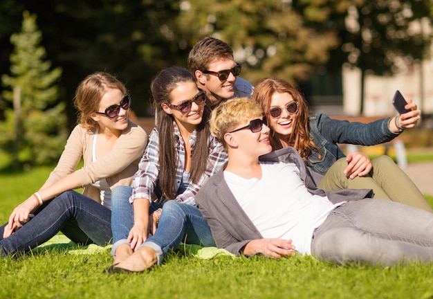 férias de verão e conceito de adolescente - grupo de adolescentes tirando foto do lado de fora com smartphone