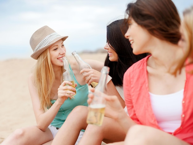 férias de verão e conceito de férias - garotas com bebidas na praia