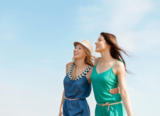 férias de verão e conceito de férias - meninas sorridentes andando na praia