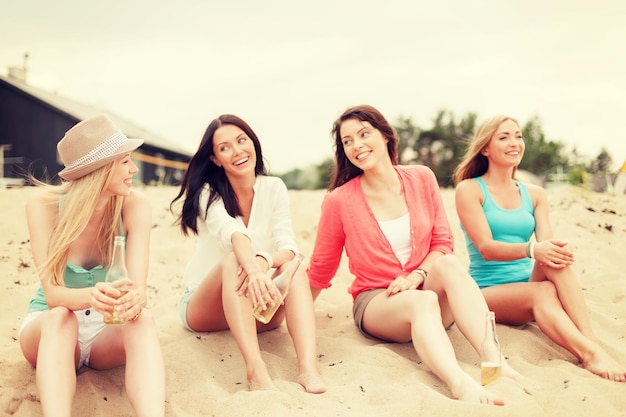 Férias de verão e conceito de férias - meninas sorridentes com bebidas na praia