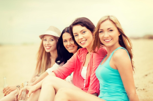 férias de verão e conceito de férias - meninas sorridentes com bebidas na praia